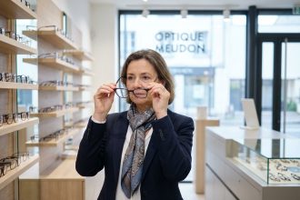Femme en tenue d'affaires examinant des montures de lunettes dans un magasin moderne