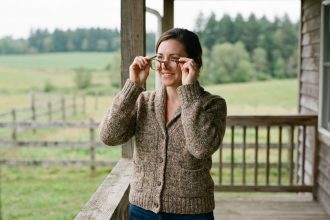 Femme souriante essayant des lunettes sur un porche rural